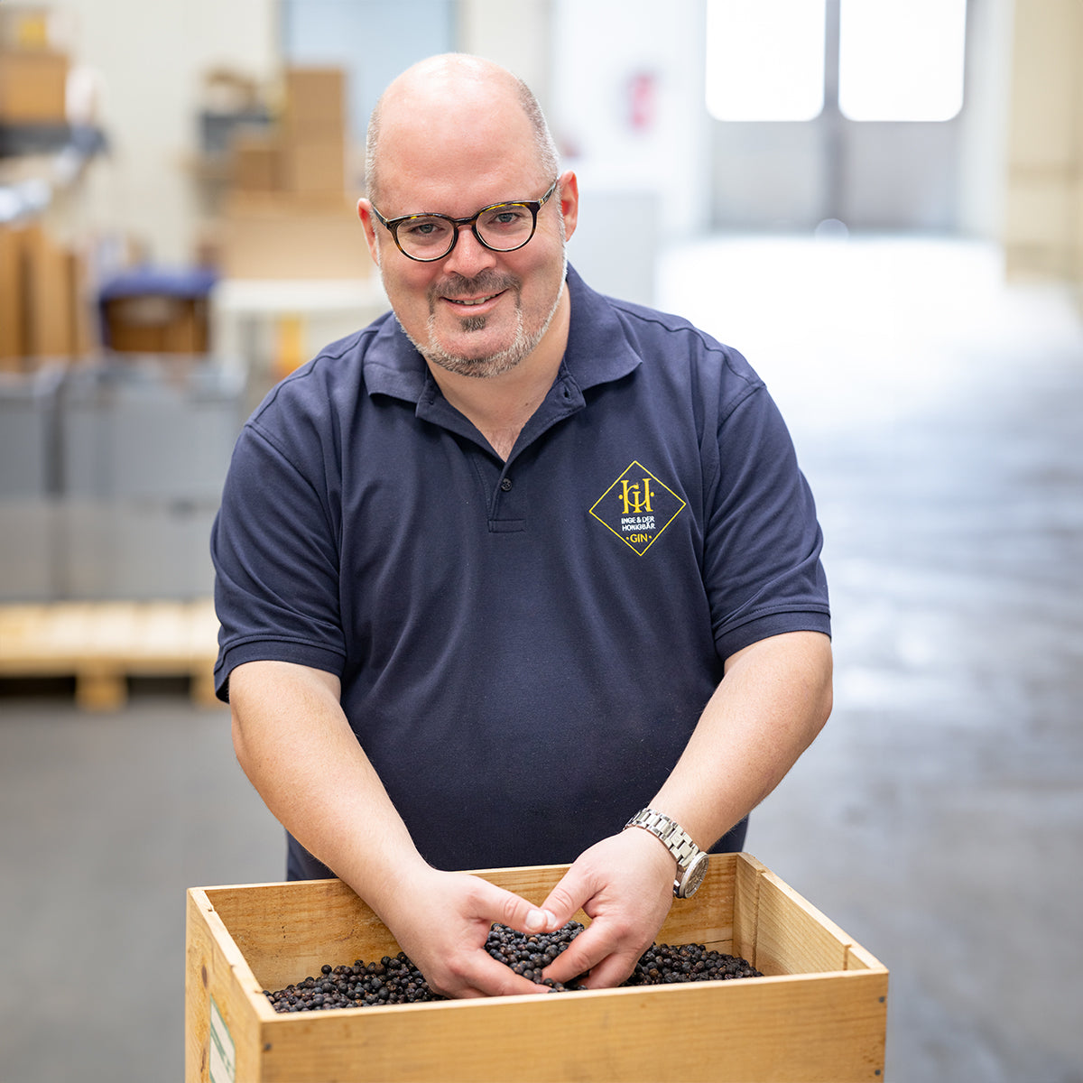 Eric Kletti, Gründer von Aromahopping, bei der Ginherstellung mit einer Kiste voller Wacholderbeeren.