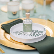 Die personalisierbare Gin-Flasche von Aromahopping für besondere Anlässe auf einem goldenen Teller präsentiert, mit grünen Akzenten.