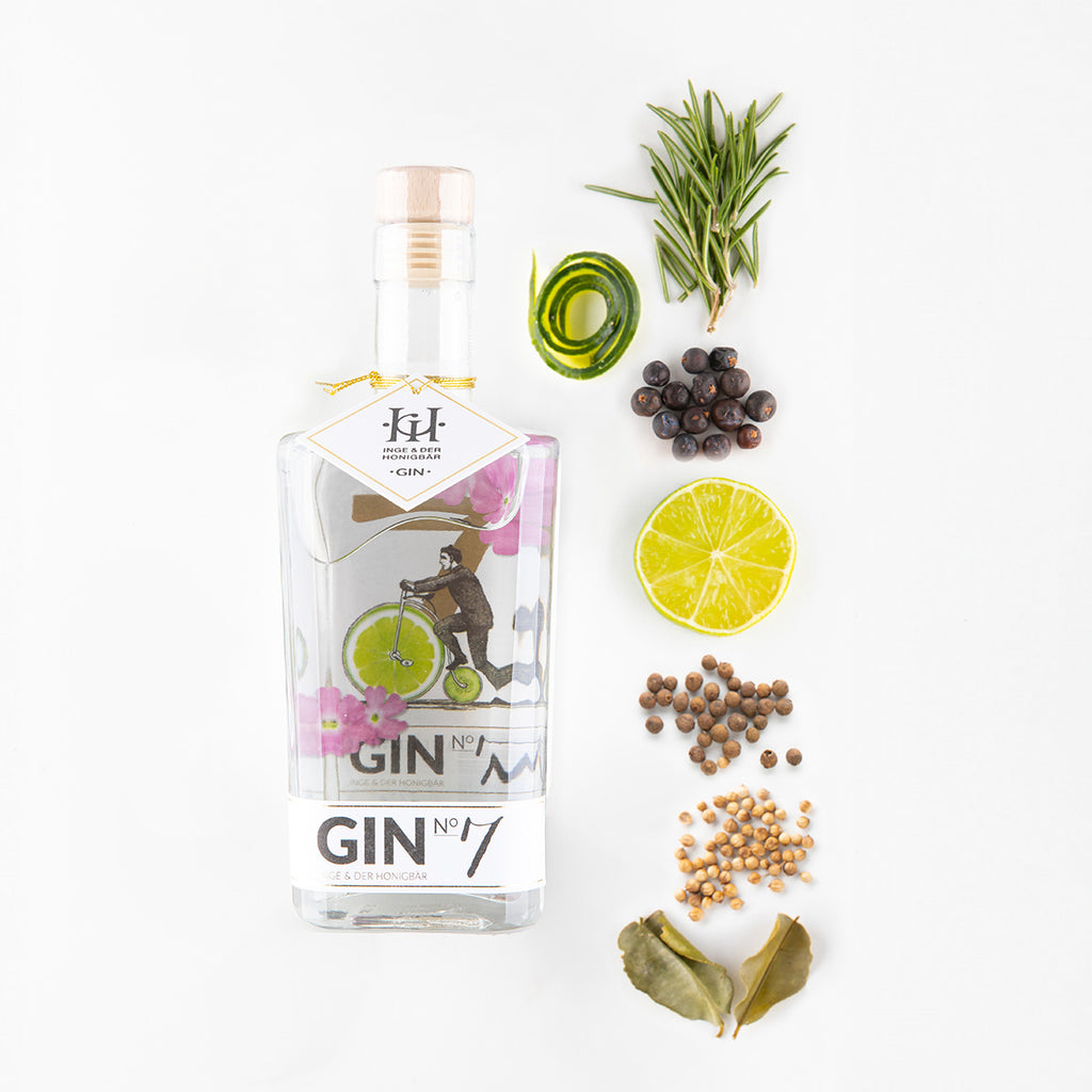 Ingredients liegen neben einer Flasche Premium-Gin NO. 7 Kaffirlimette & Zimt von Inge und der Honigbär, auf weißem Hintergrund.