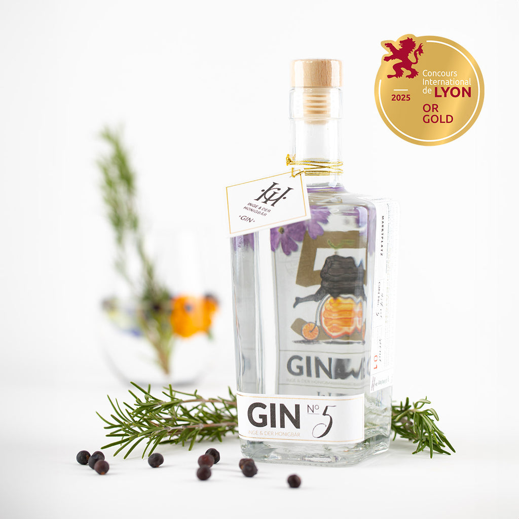 Eine Flasche des regionalen Premium-Gins NO. 5 von Inge und der Honigbär, umringt von hochwertigen Zutaten wie Rosmarin und Wacholder.