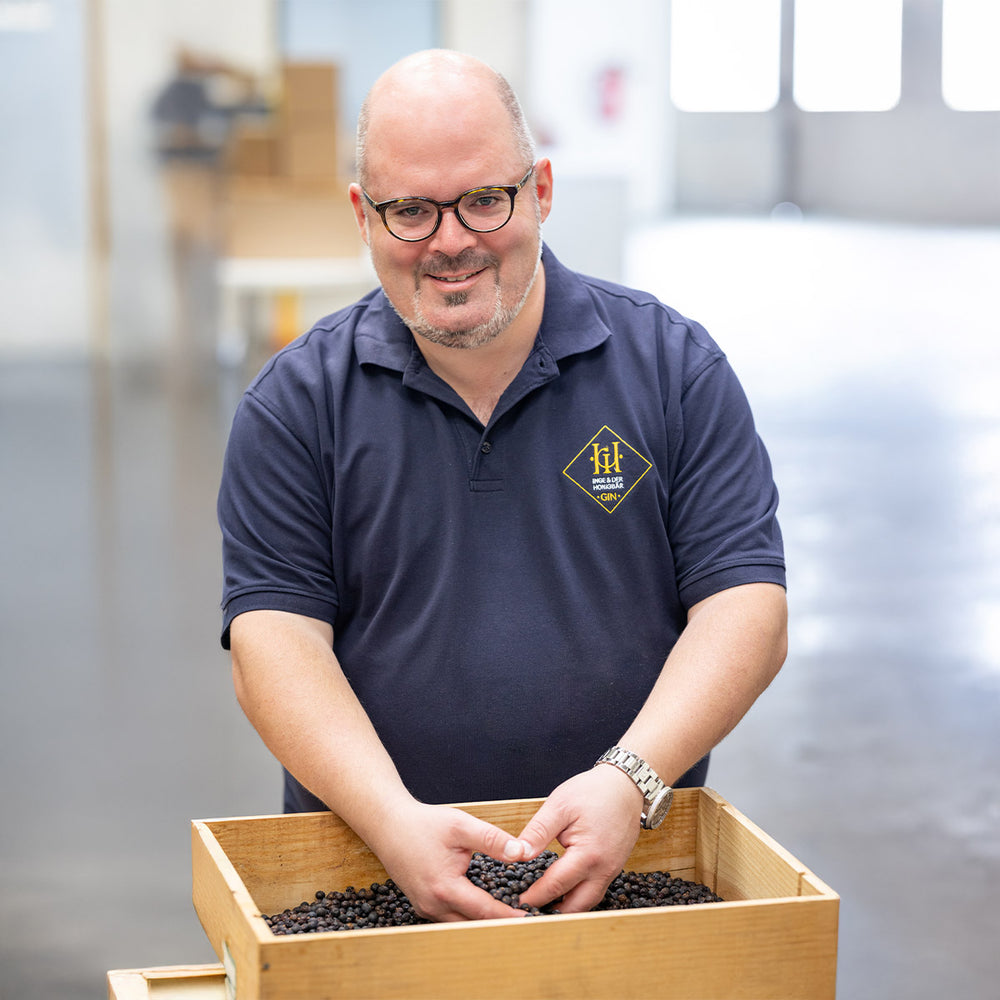 Aromahopping Gründer Eric Kletti vor einer Kiste mit Wacholder