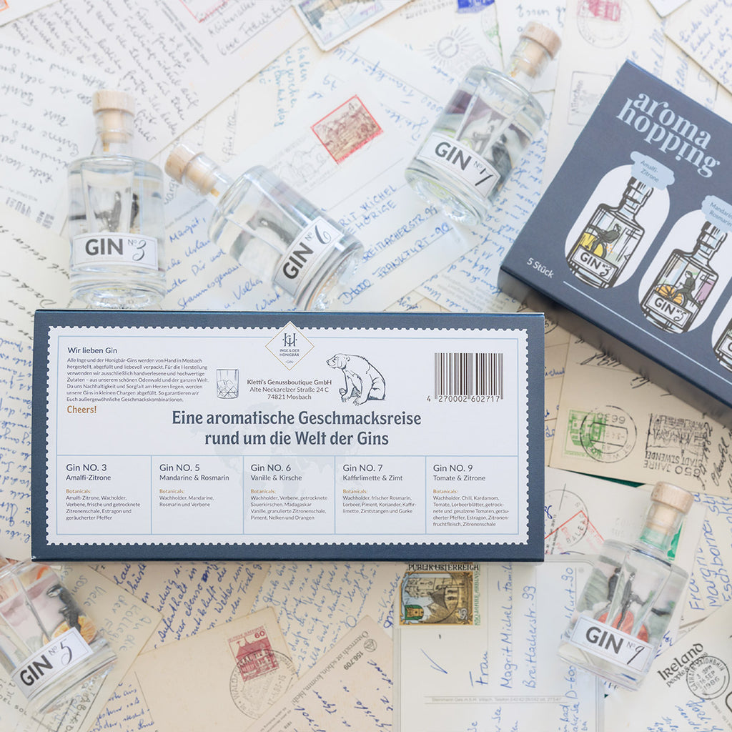 Rückseite der Aromahopping Probierbox, umringt von den fünf kleinen Premium-Gins, die Teil der Geschmacksreise sind.
