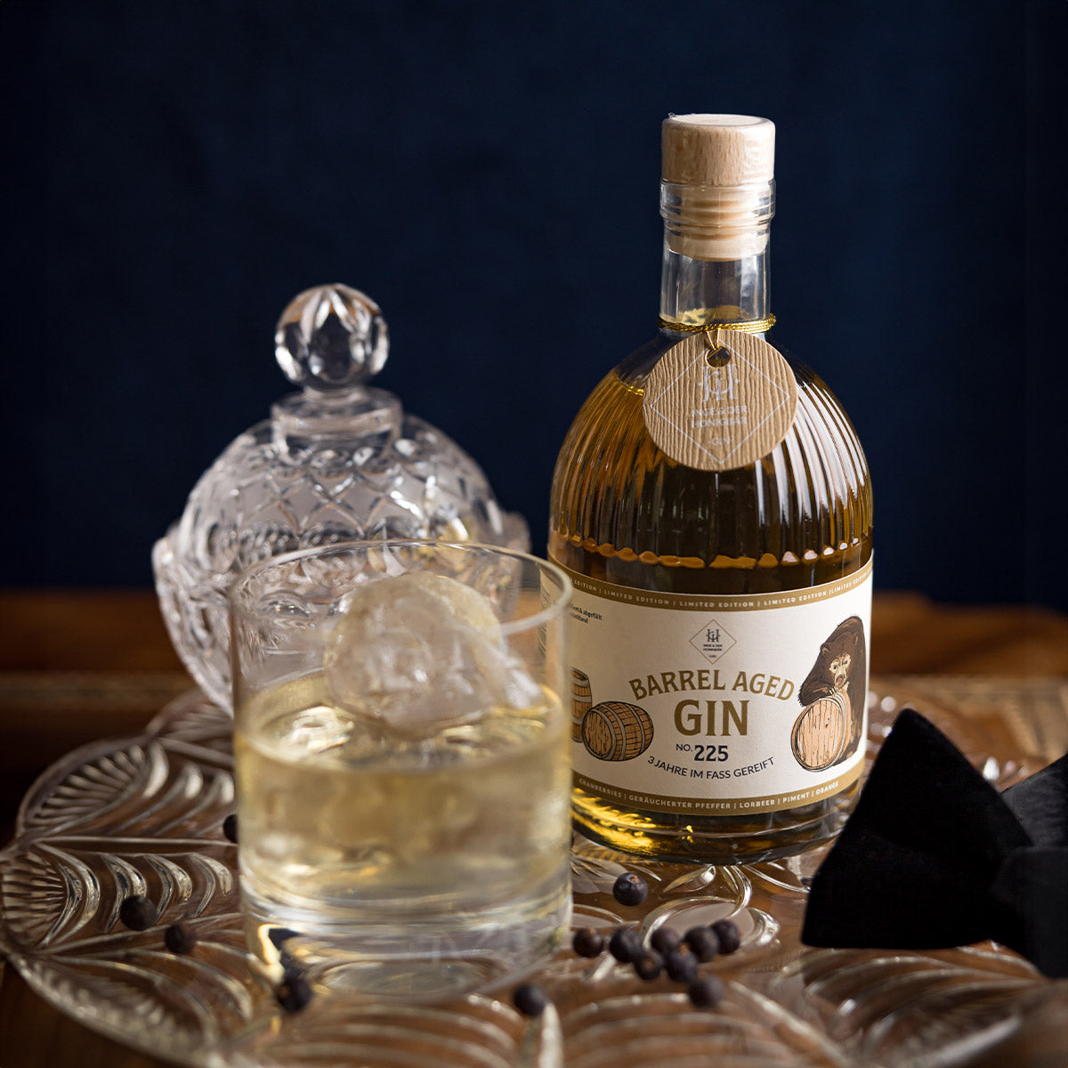Ein Glas und eine Flasche handgefertigter Barrel Aged Gin von Inge und der Honigbär auf einem Tablett.