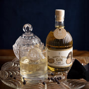 Ein Glas und eine Flasche handgefertigter Barrel Aged Gin von Inge und der Honigbär auf einem Tablett.